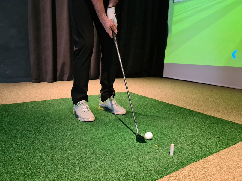 Golf player playing golf indoors on golf simulator closeup